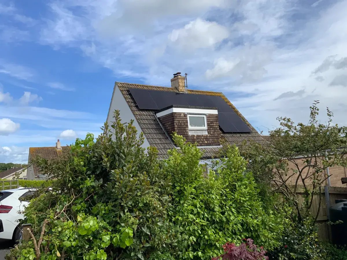 Residential house with all-black solar panels on Devon roof, blue sky