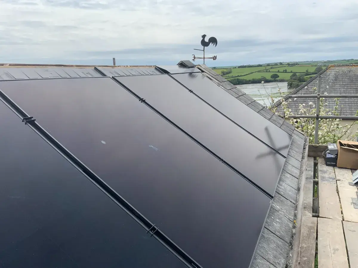 In-roof solar panels on slate with Devon estuary and weather vane