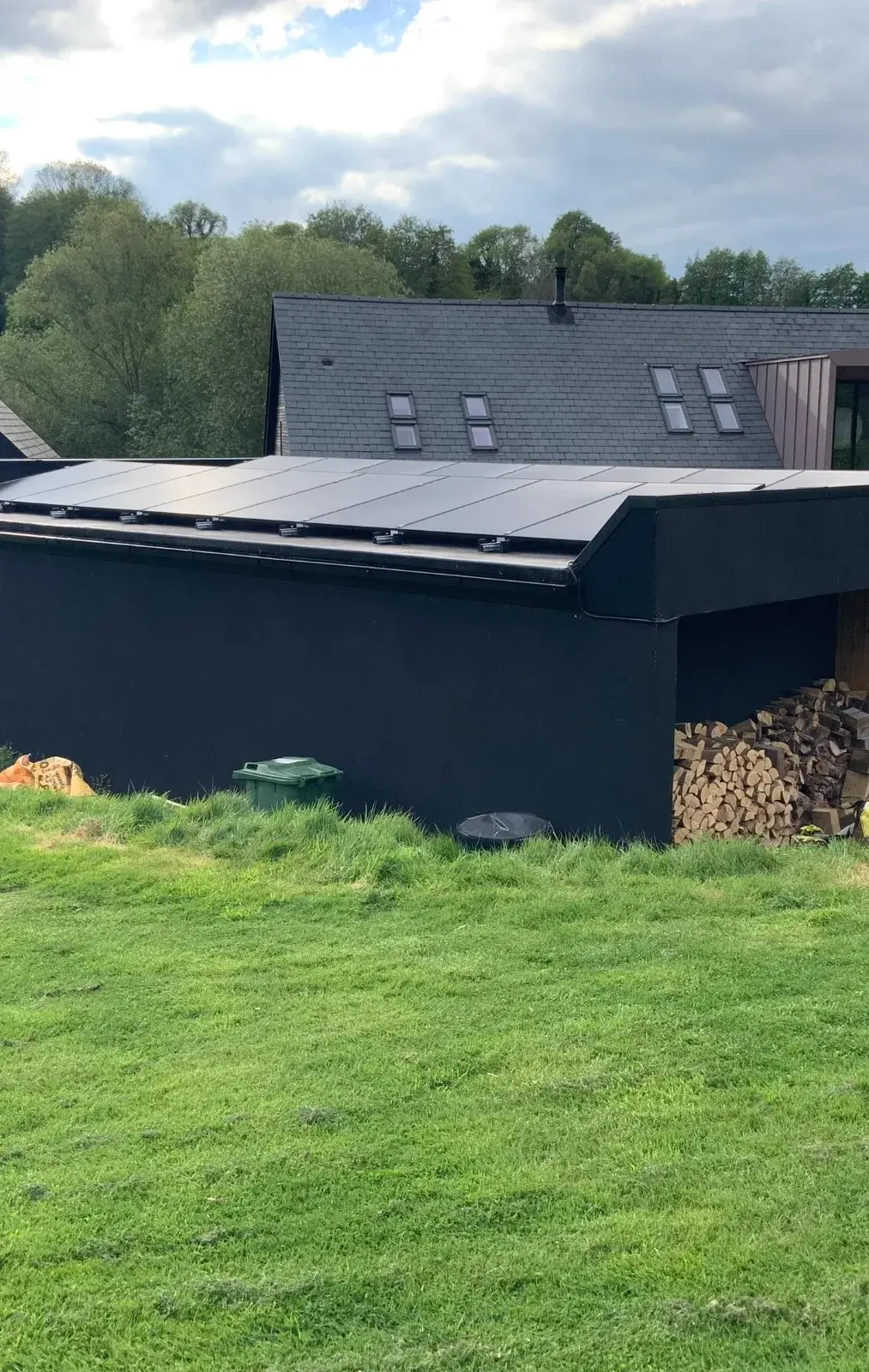 All-black solar panels on modern flat-roofed black extension, green field