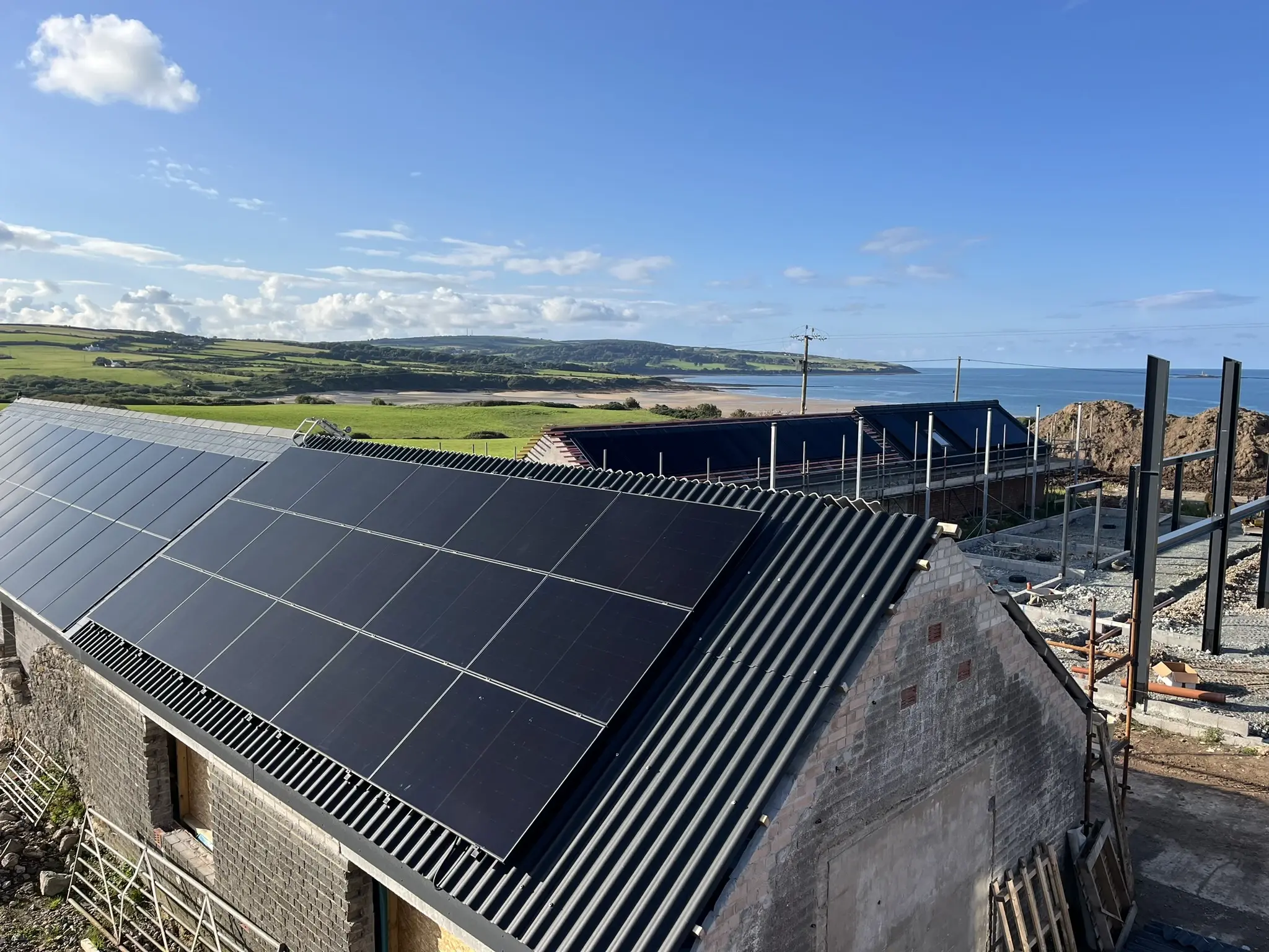 Solar panels on coastal barn roof with sea and fields in Devon
